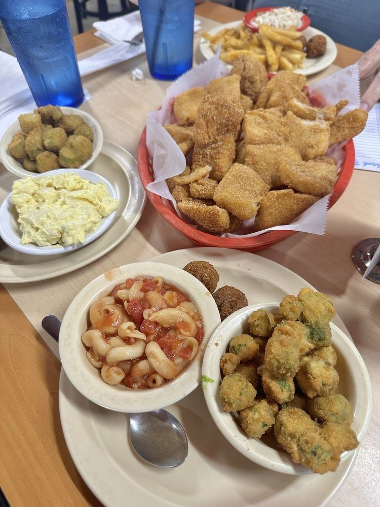 A basket of fried catfish with fried okra, mac and tomato and potato salad
