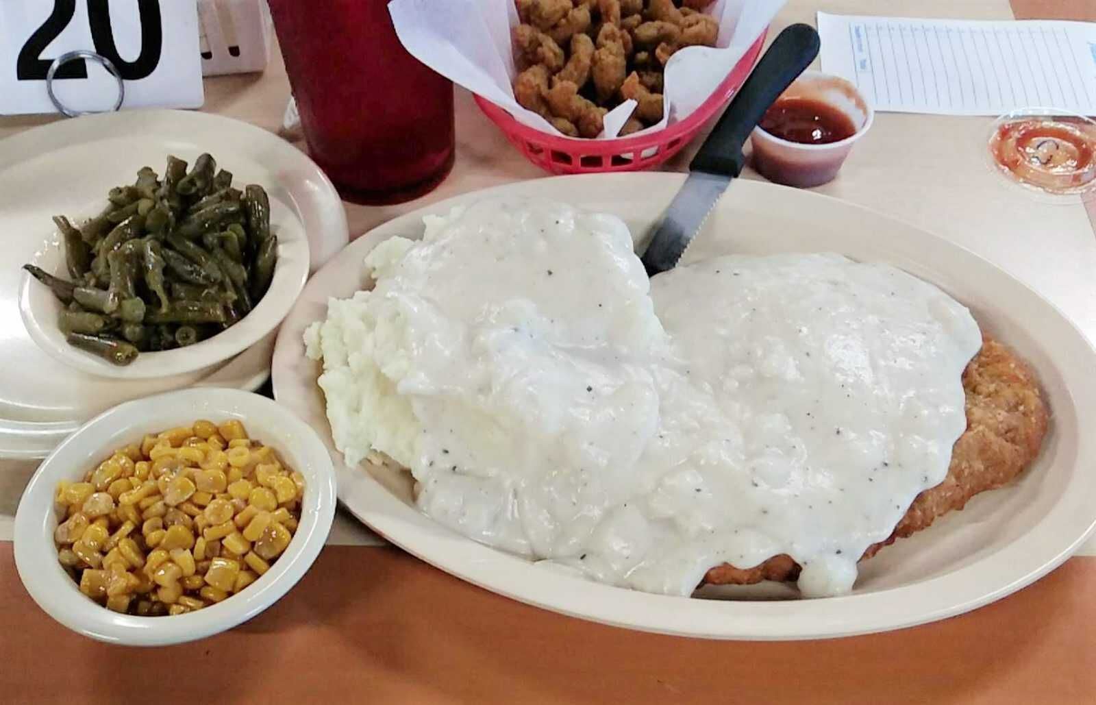 Country fried steak smothered in white gravy with green beans and corn